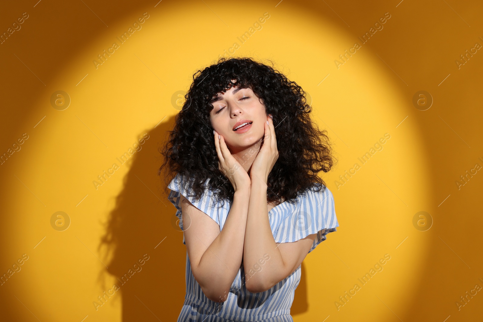 Photo of Beautiful young woman in sunlight on orange background