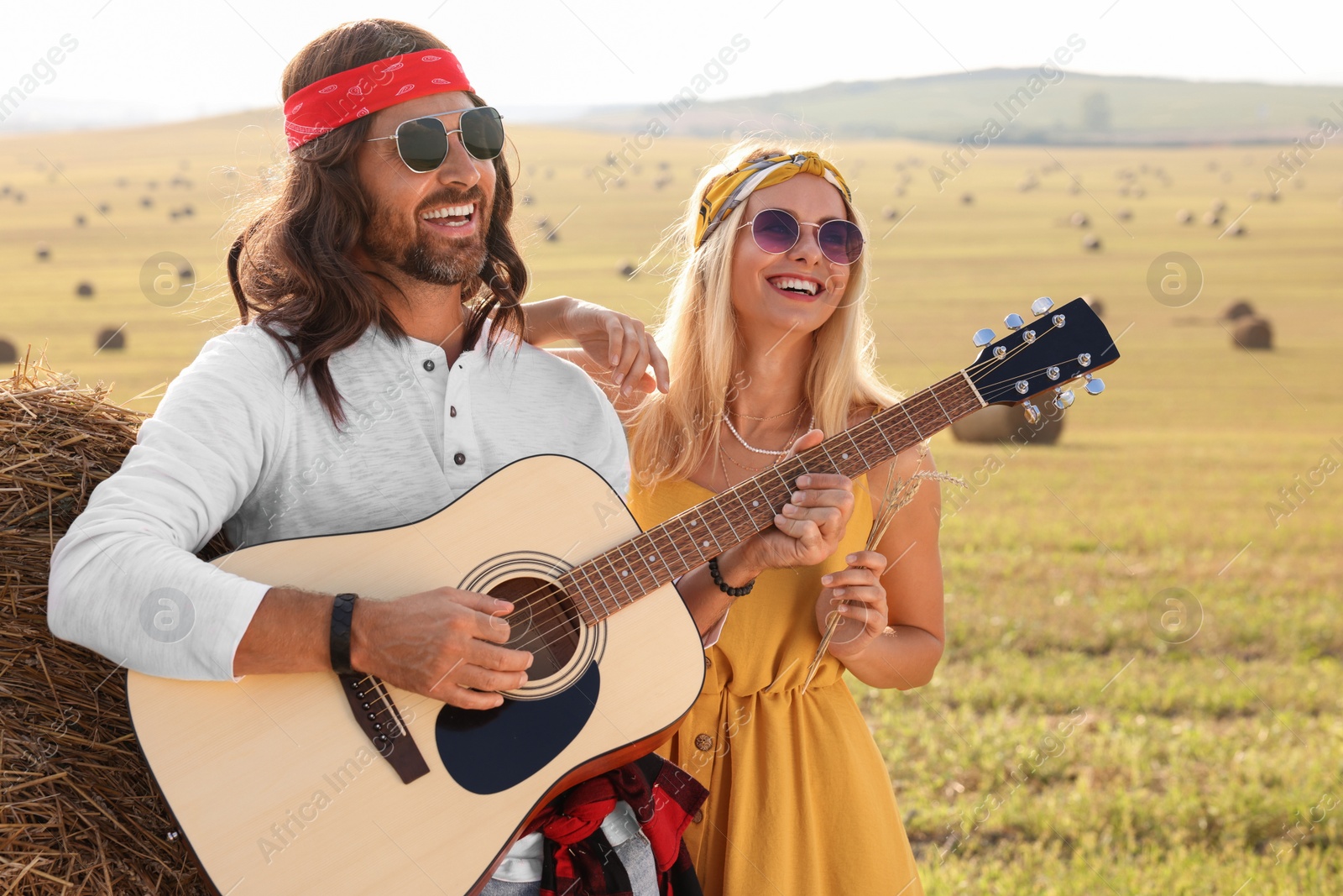 Photo of Beautiful hippie woman listening to her friend playing guitar in field