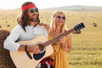Beautiful hippie woman listening to her friend playing guitar in field