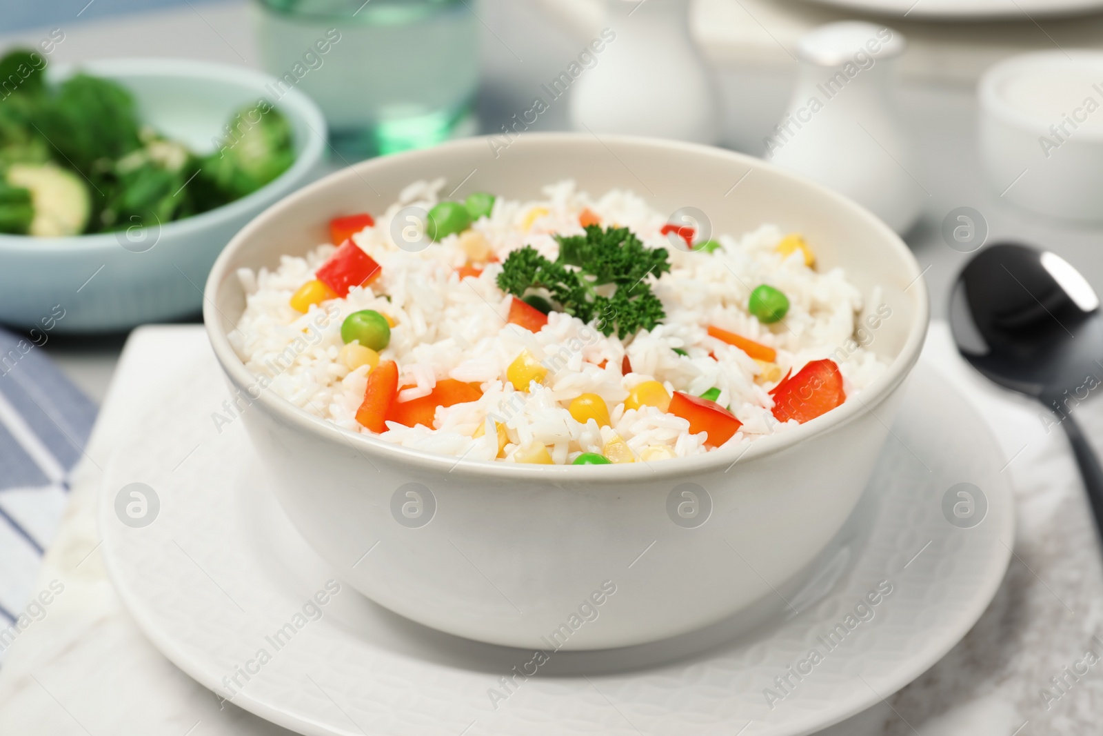 Photo of Bowl of boiled rice with vegetables on table