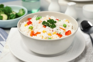 Photo of Bowl of boiled rice with vegetables on table