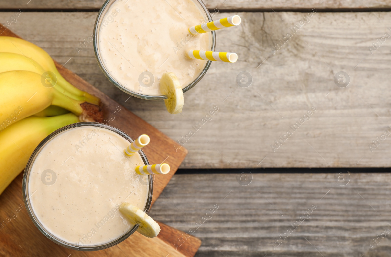 Photo of Glasses with banana smoothie on wooden table, flat lay. Space for text