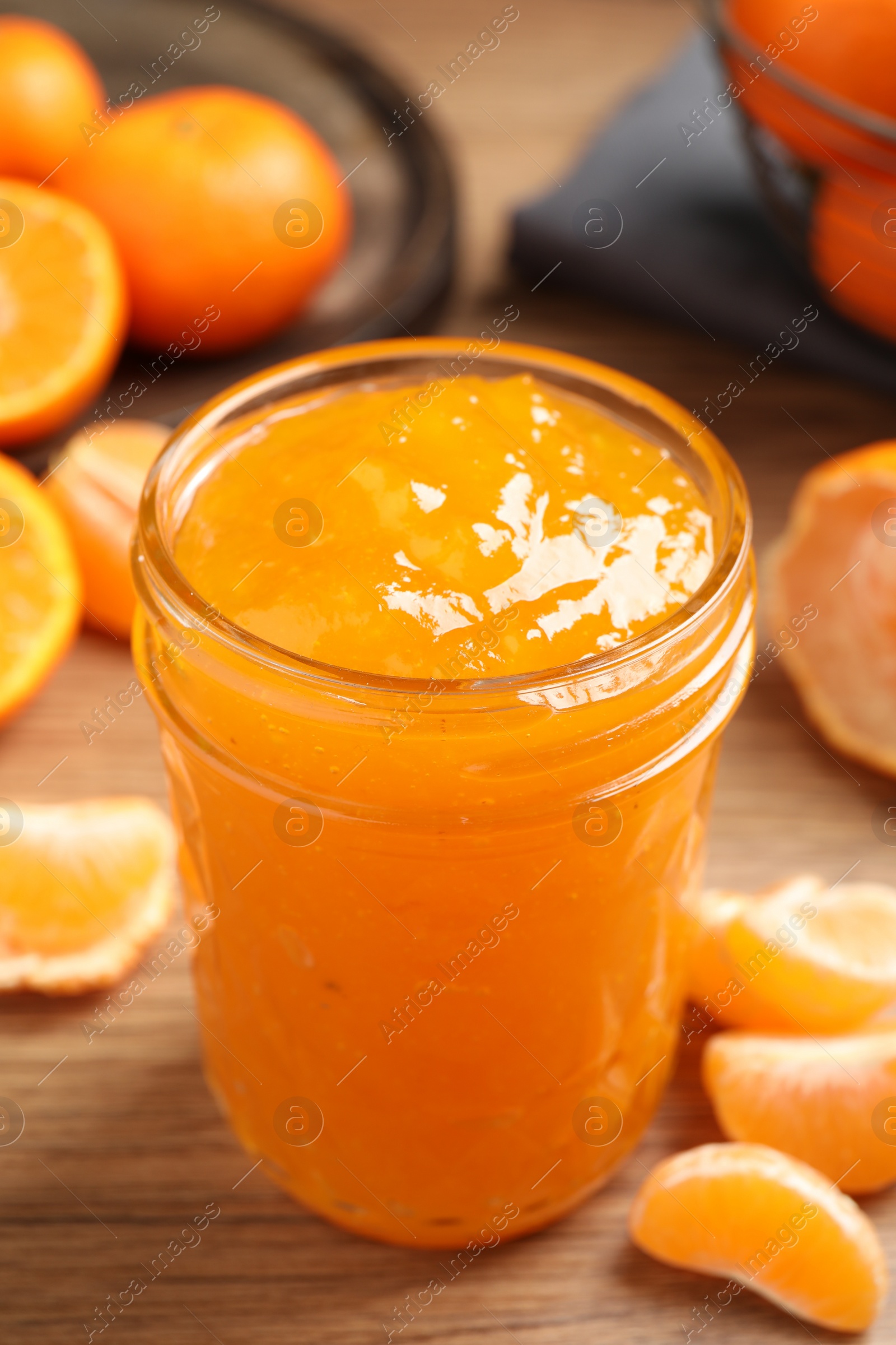 Photo of Delicious tangerine jam on wooden table, closeup