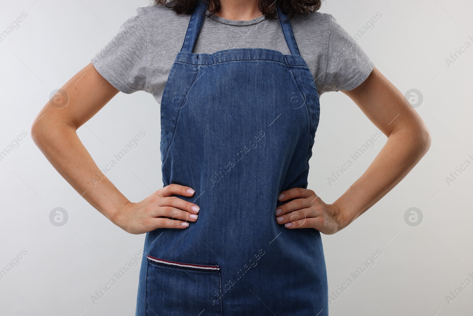 Photo of Woman wearing kitchen apron on light grey background, closeup. Mockup for design