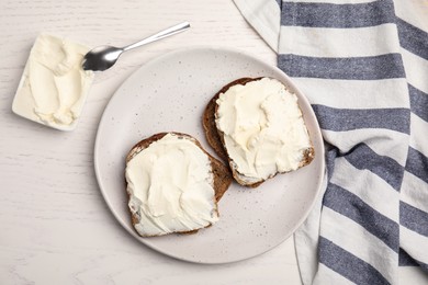 Photo of Bread with cream cheese on white wooden table, flat lay