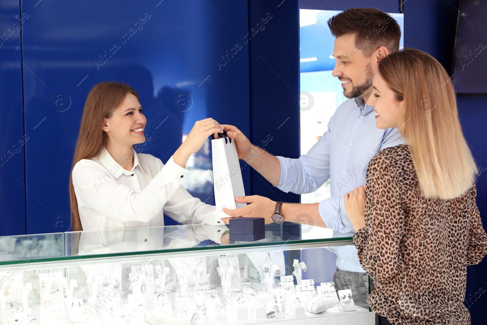 Photo of Saleswoman giving purchase to customers in jewelry store