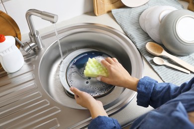 Photo of Woman washing plate in kitchen sink, above view