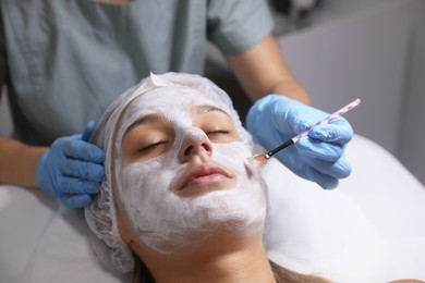 Cosmetologist applying mask on client's face in spa salon