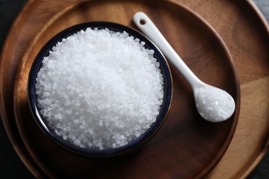 Photo of Organic white salt in bowl and spoon on table, above view