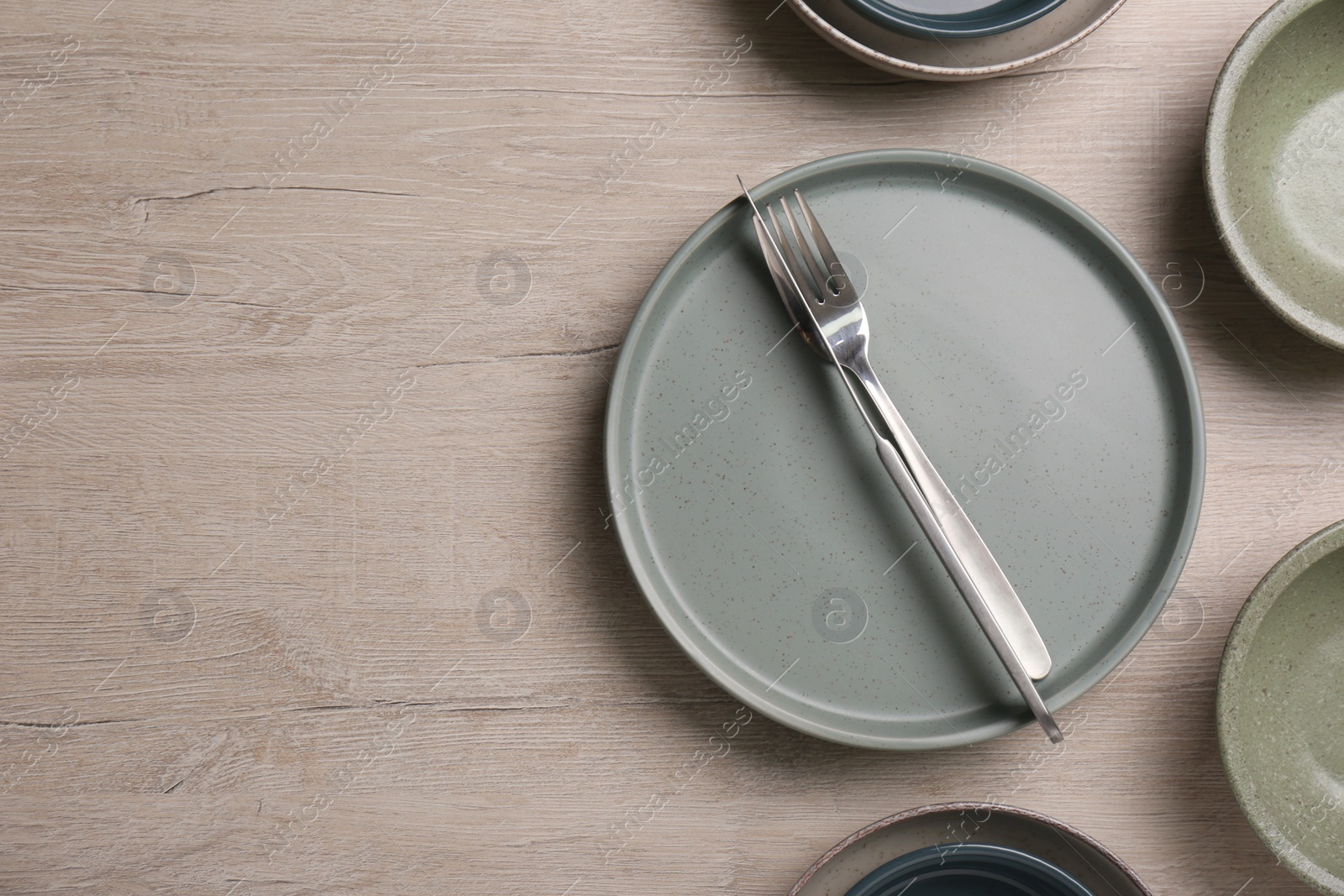 Photo of Different plates, bowls and cutlery on wooden table, flat lay. Space for text