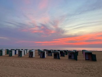 Photo of Many wooden beach huts on seacoast at sunset