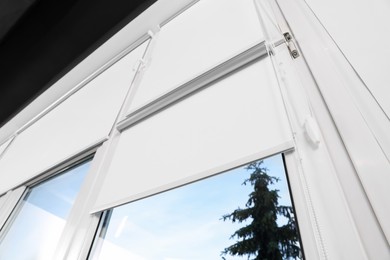 Photo of Window with white roller blinds indoors, low angle view