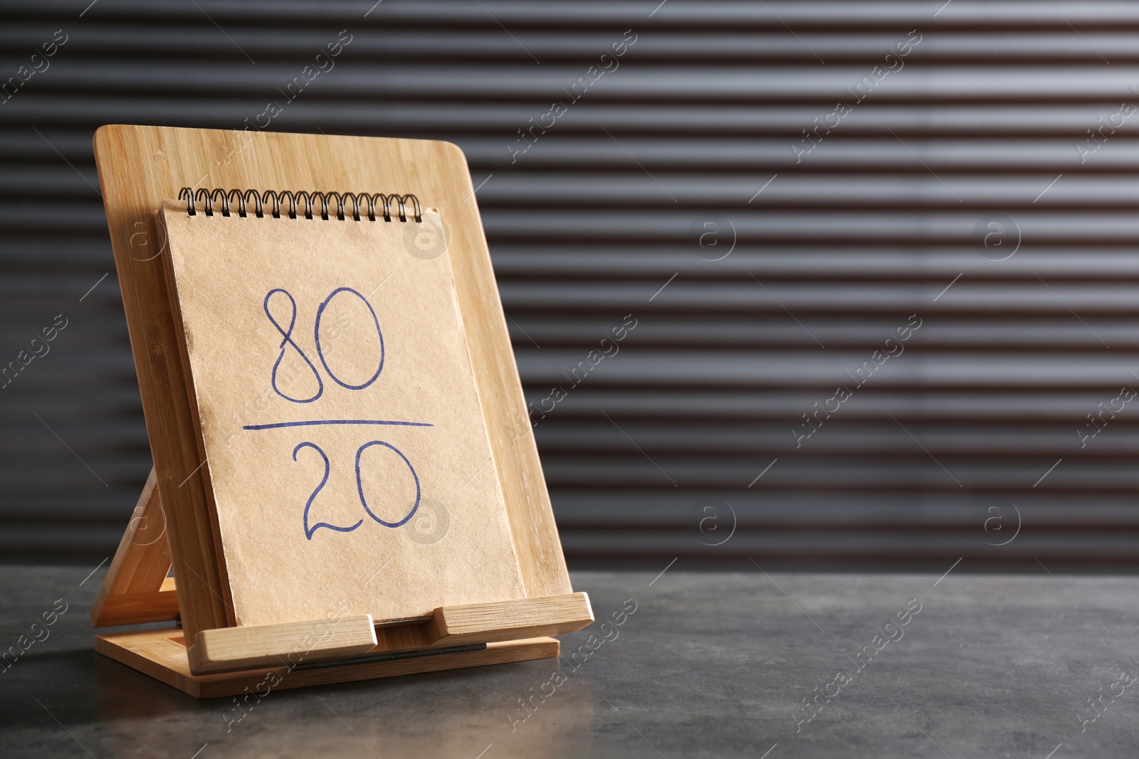 Photo of Notebook with 80/20 rule representation on grey stone table, space for text. Pareto principle concept