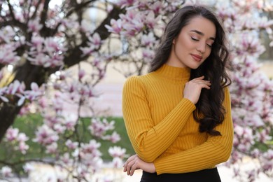 Beautiful woman near blossoming magnolia tree on spring day