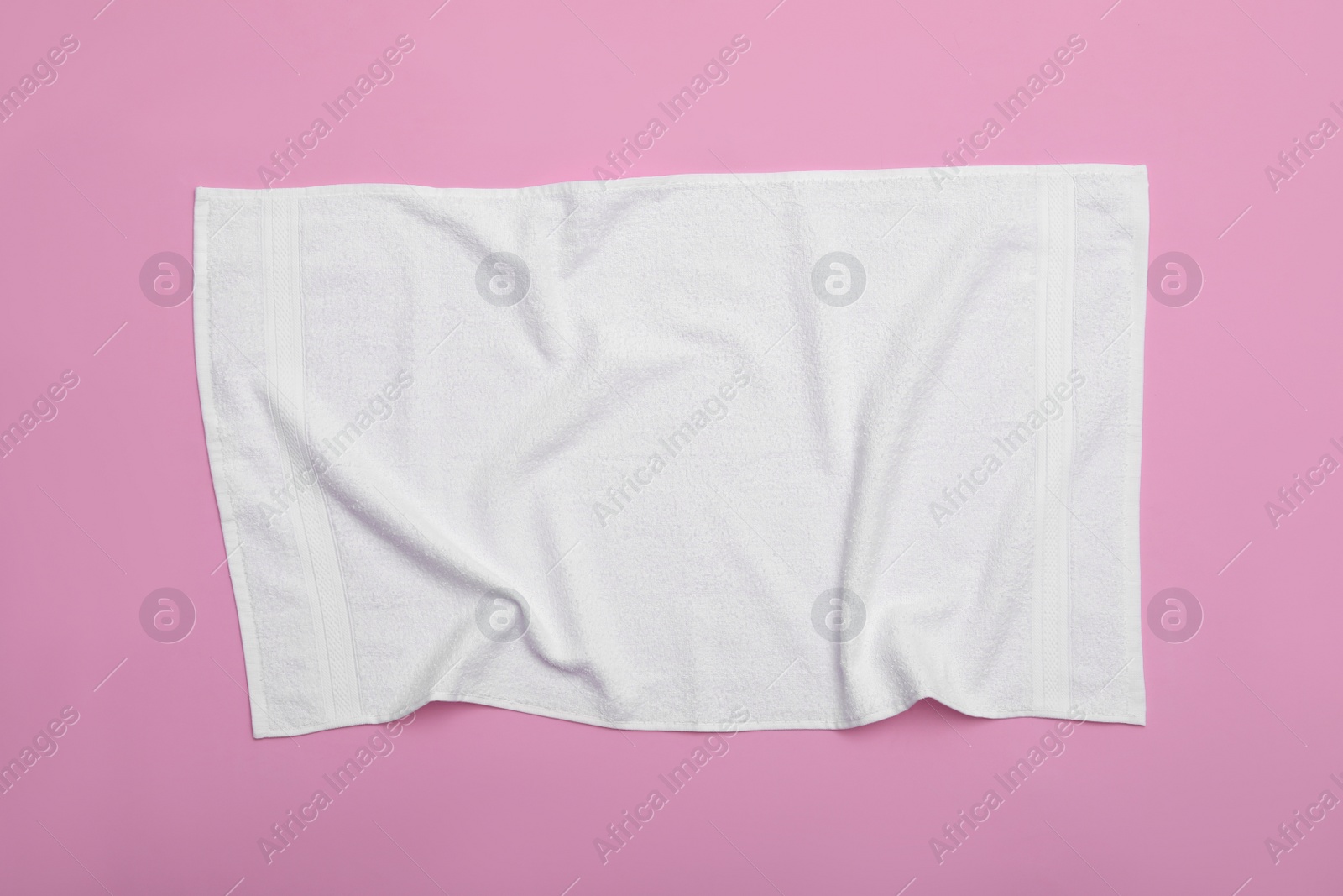 Photo of Crumpled white beach towel on pink background, top view
