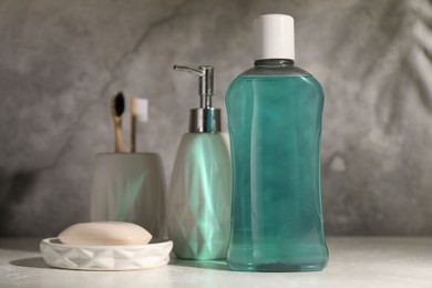 Photo of Bottle of mouthwash, toothbrushes and soap on light table in bathroom