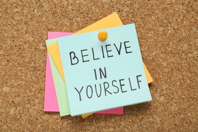 Photo of Notes with phrase Believe In Yourself pinned on corkboard, top view. Motivational quote
