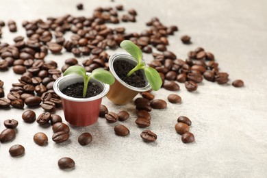 Photo of Coffee capsules with seedlings and beans on light grey table, closeup. Space for text
