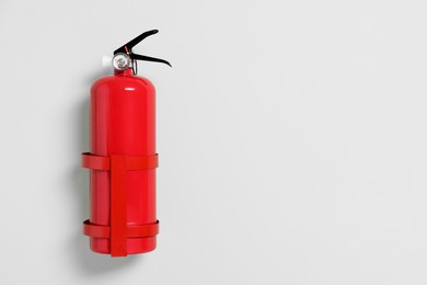 Red fire extinguisher on light green background. Space for text