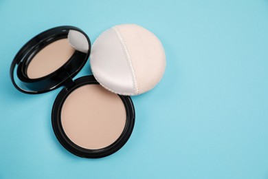 Photo of Face powder and puff on light blue background, flat lay. Space for text