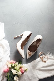 Photo of Flat lay composition with wedding dress, white high heel shoes and flowers on grey background. Space for text