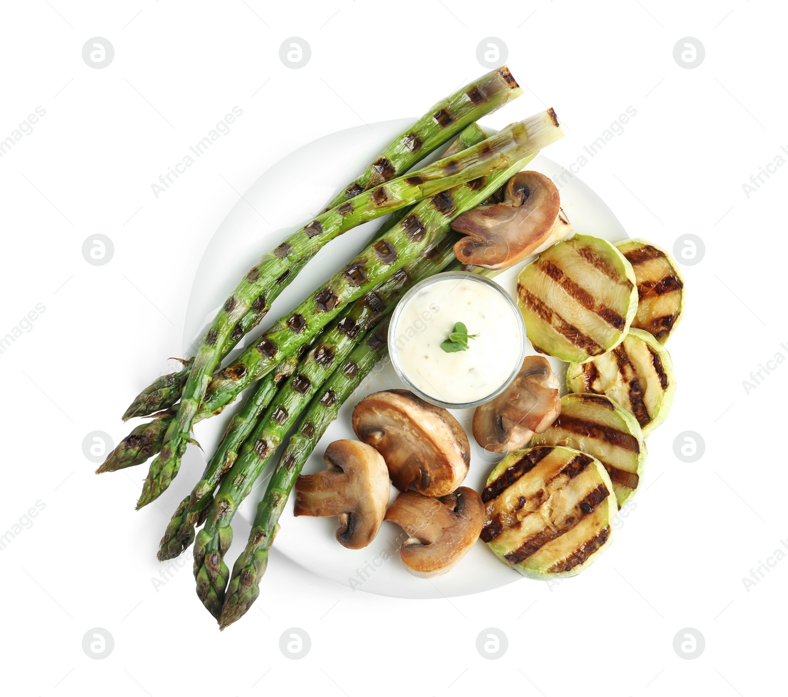 Photo of Tasty grilled asparagus with sauce, zucchini and mushrooms isolated on white, top view