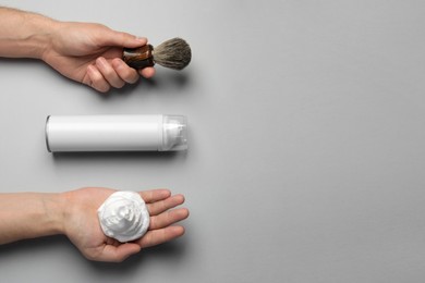 Photo of Man with shaving foam, brush and bottle on light grey background, top view. Space for text