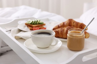 Photo of Good morning. Tray with tasty breakfast on bed, closeup