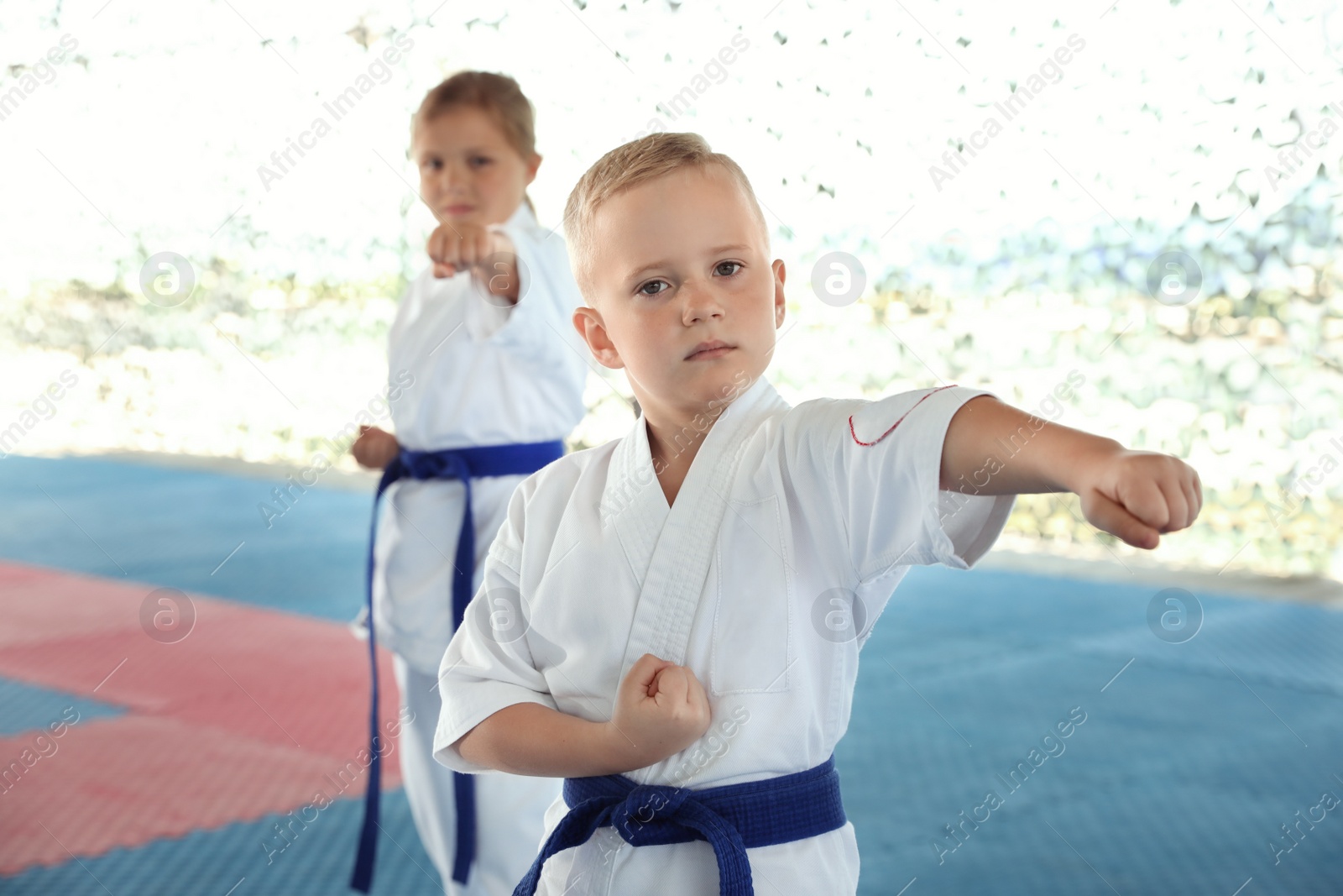 Photo of Children in kimono practicing karate on tatami outdoors