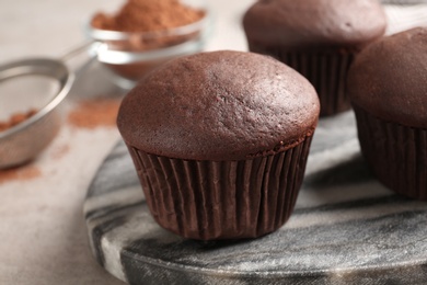 Photo of Delicious fresh chocolate cupcakes on grey marble board, closeup