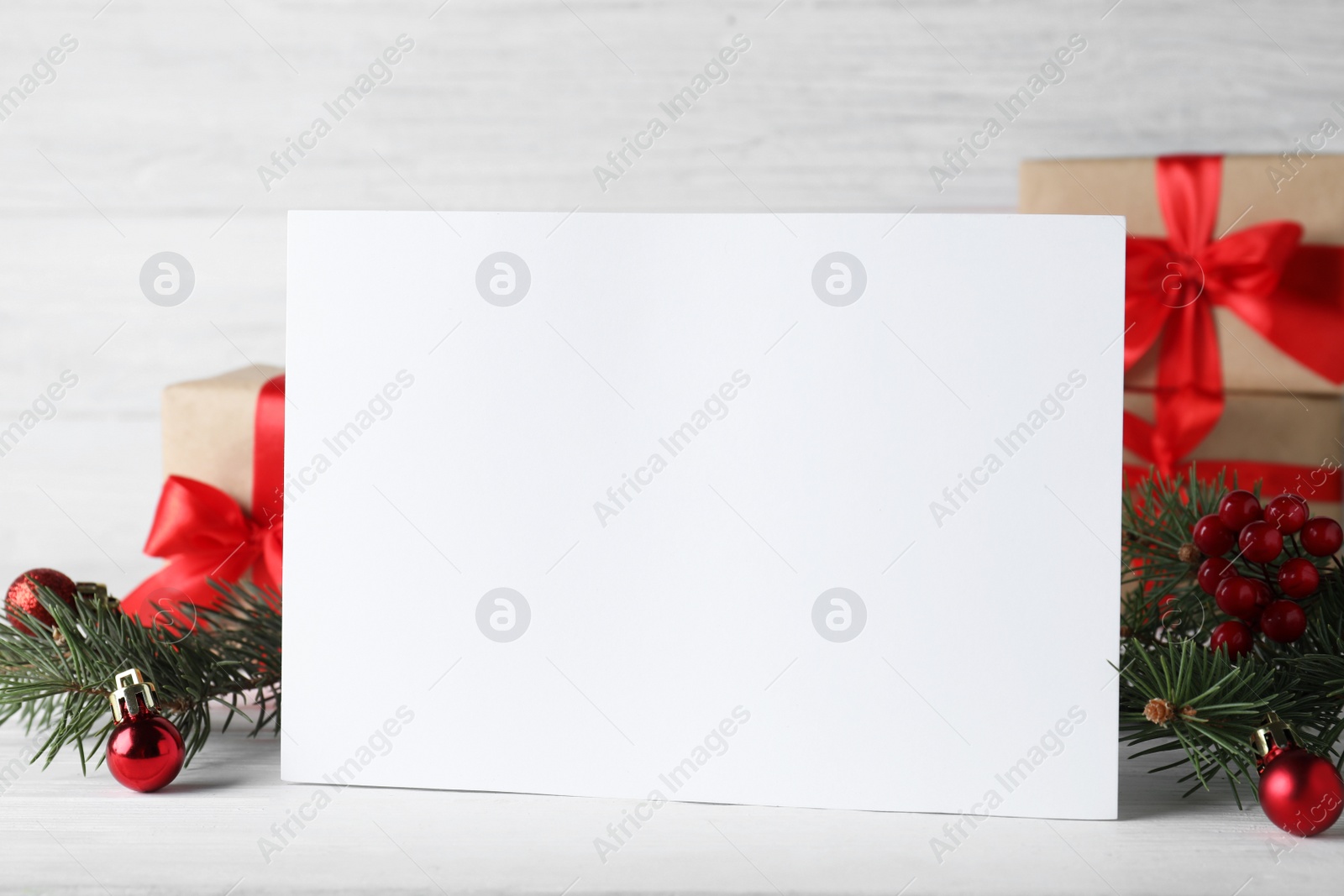 Photo of Blank greeting card near Christmas decorations on white table, closeup. Space for text