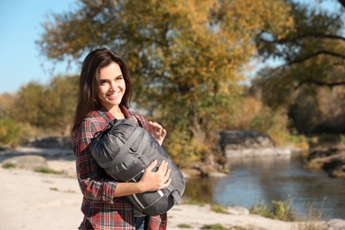 Female camper with sleeping bag near pond. Space for text