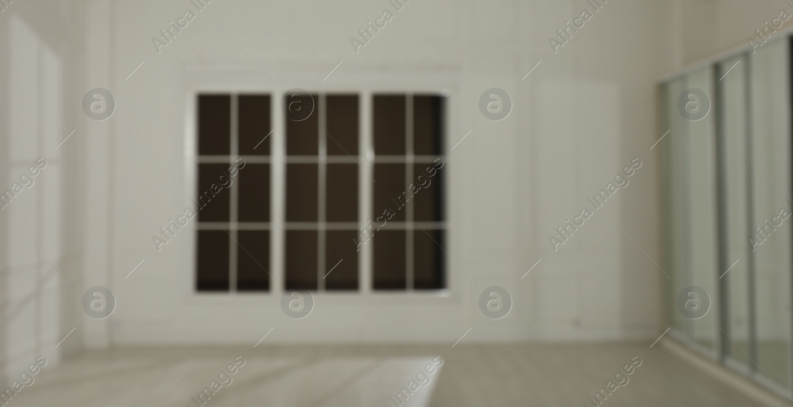 Photo of Empty room with white walls and large window, blurred view