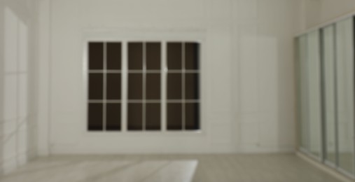 Photo of Empty room with white walls and large window, blurred view