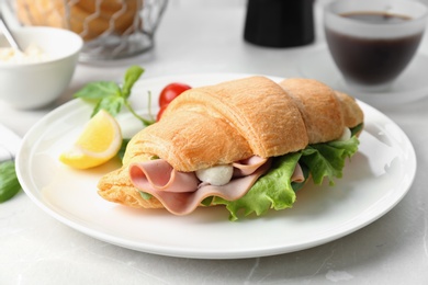 Photo of Tasty croissant sandwich with sausage  on table