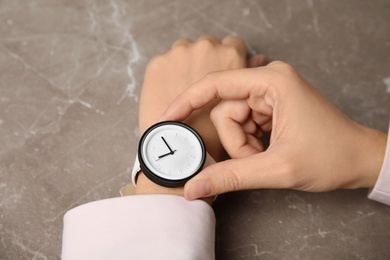 Businesswoman with stylish wrist watch at table, closeup. Time management