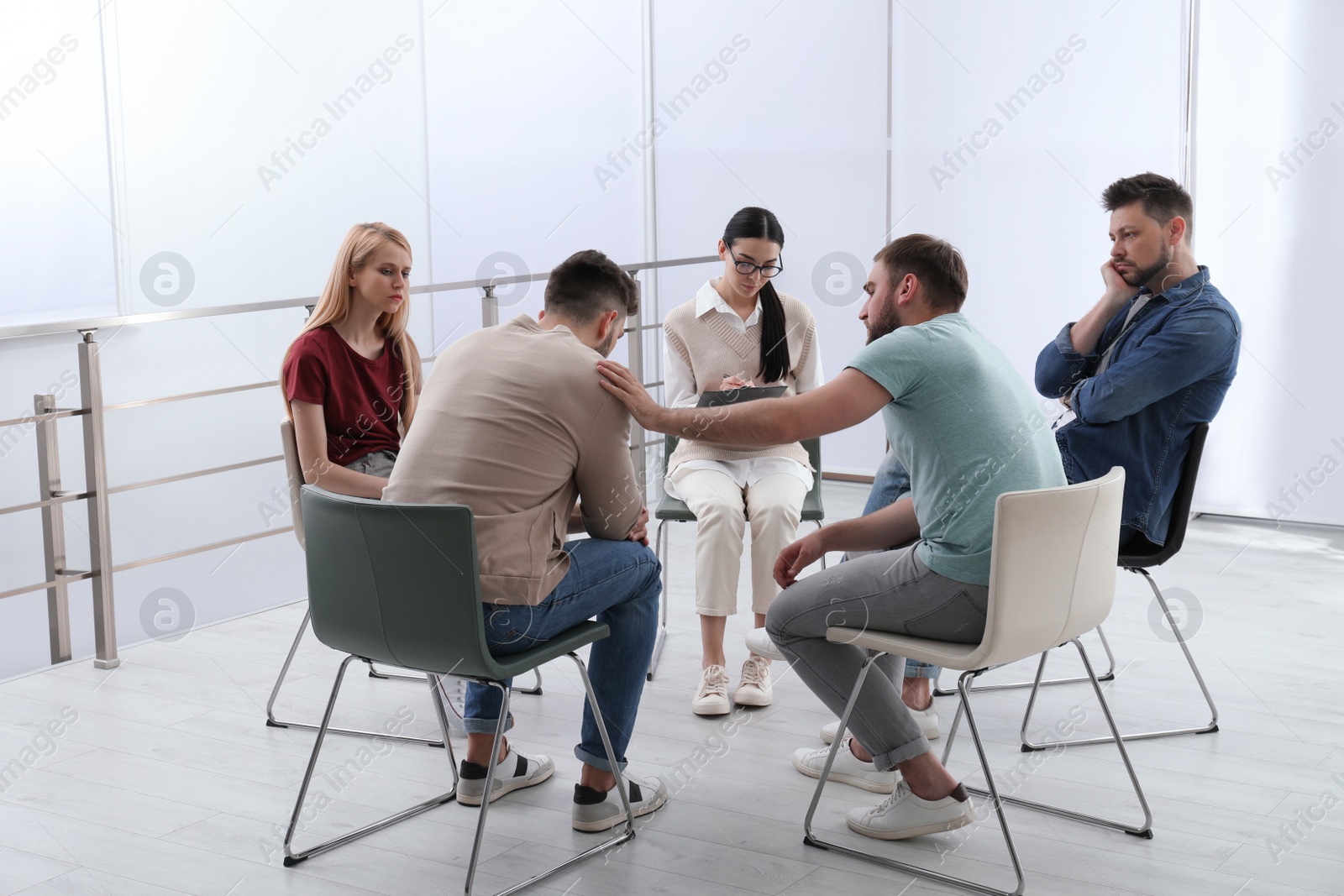 Photo of Psychotherapist working with group of drug addicted people at therapy session indoors