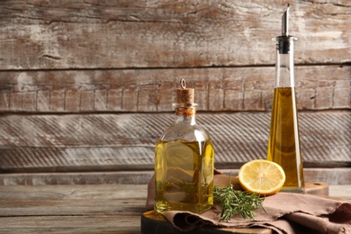 Different bottles with rosemary oil against wooden background