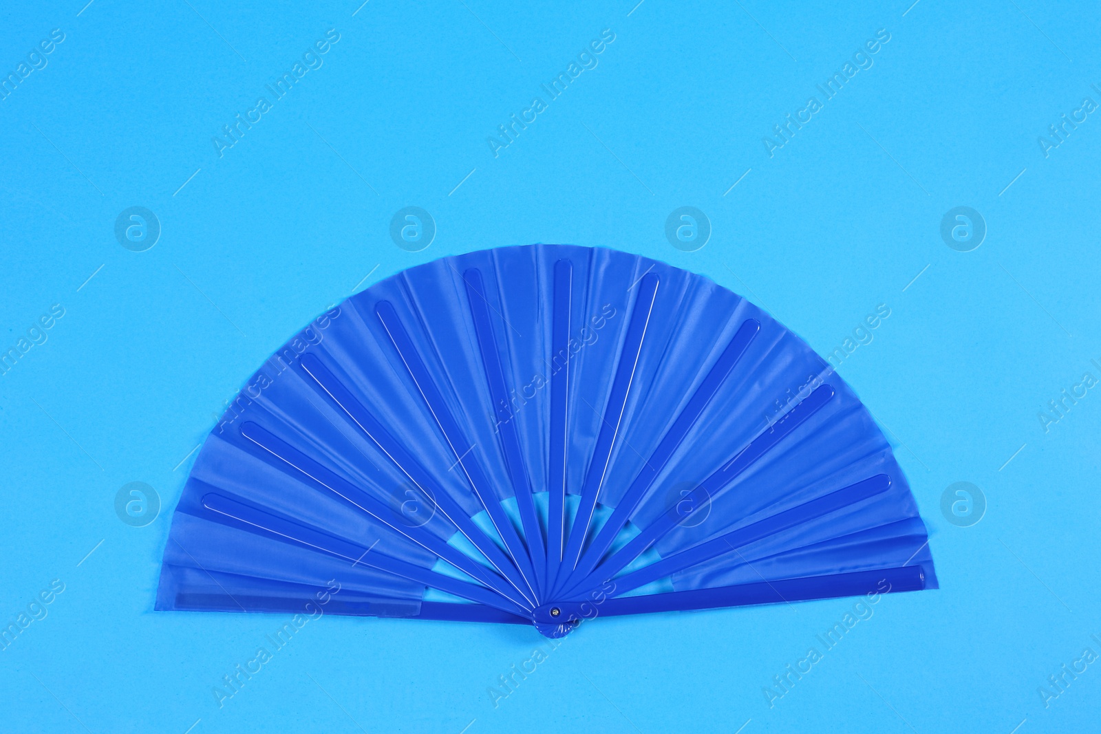 Photo of Hand fan on light blue background, top view