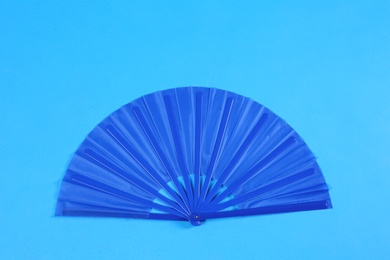 Photo of Hand fan on light blue background, top view