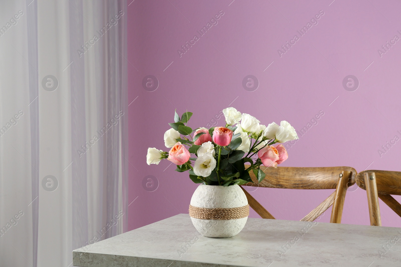 Photo of Vase with beautiful flowers as element of interior design on table in room