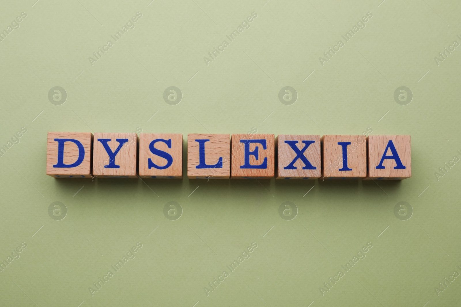 Photo of Wooden cubes with word Dyslexia on olive background, flat lay