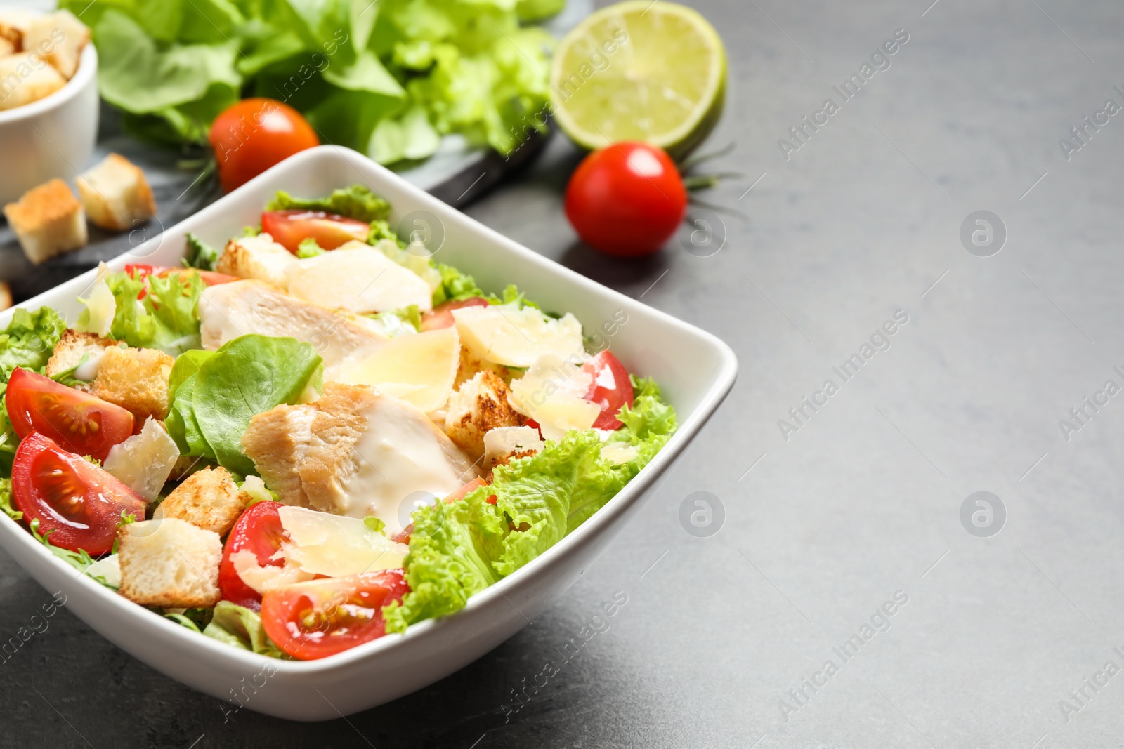 Photo of Delicious fresh Caesar salad in bowl on grey table