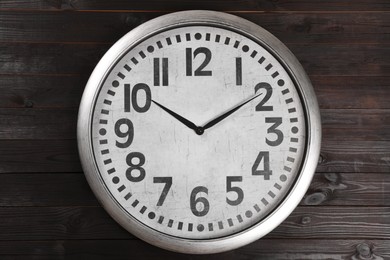 Photo of Stylish analog clock hanging on wooden wall