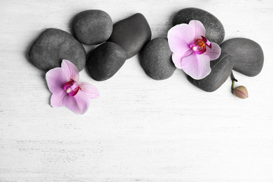 Photo of Stones with orchid flowers and space for text on white wooden background, flat lay. Zen lifestyle