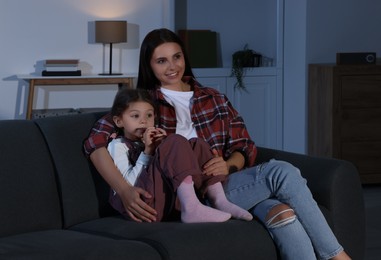 Mother and daughter watching TV at home in evening