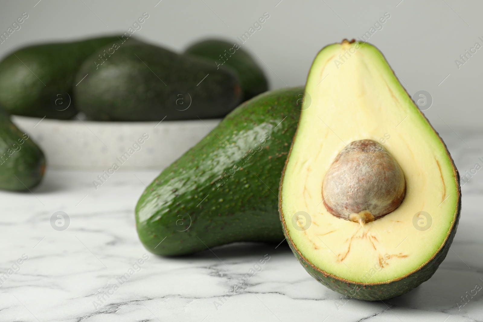 Photo of Delicious ripe avocados on white marble table