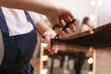 Photo of Stylist cutting hair of client in professional salon, closeup