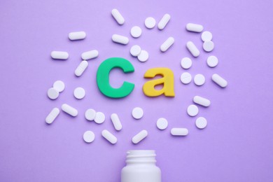 Photo of Symbol Ca (Calcium), medical bottle and pills on violet background, top view