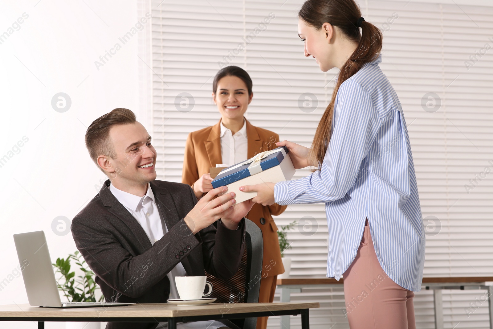 Photo of Woman presenting gift to her colleague in office